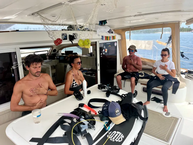 Freediving theory briefing on board, with masks and fins laid out in the cockpit.