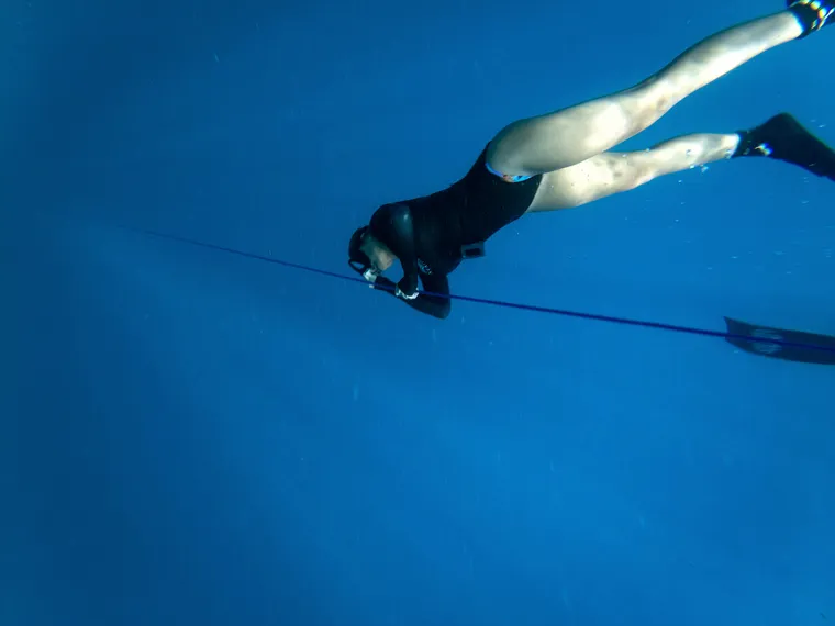 A freediver gliding horizontally along the line.