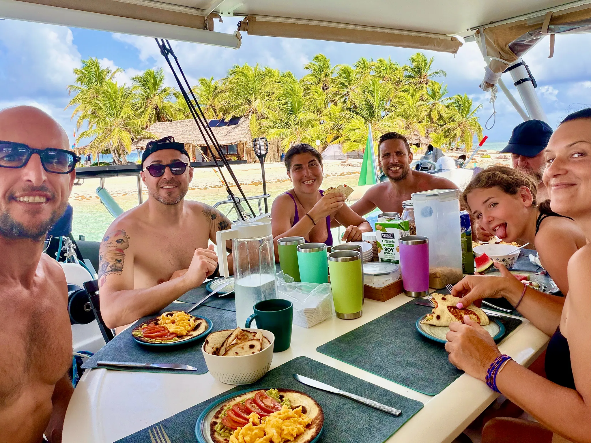 Il gruppo a colazione al tavolo del pozzetto, con l’isola alle spalle