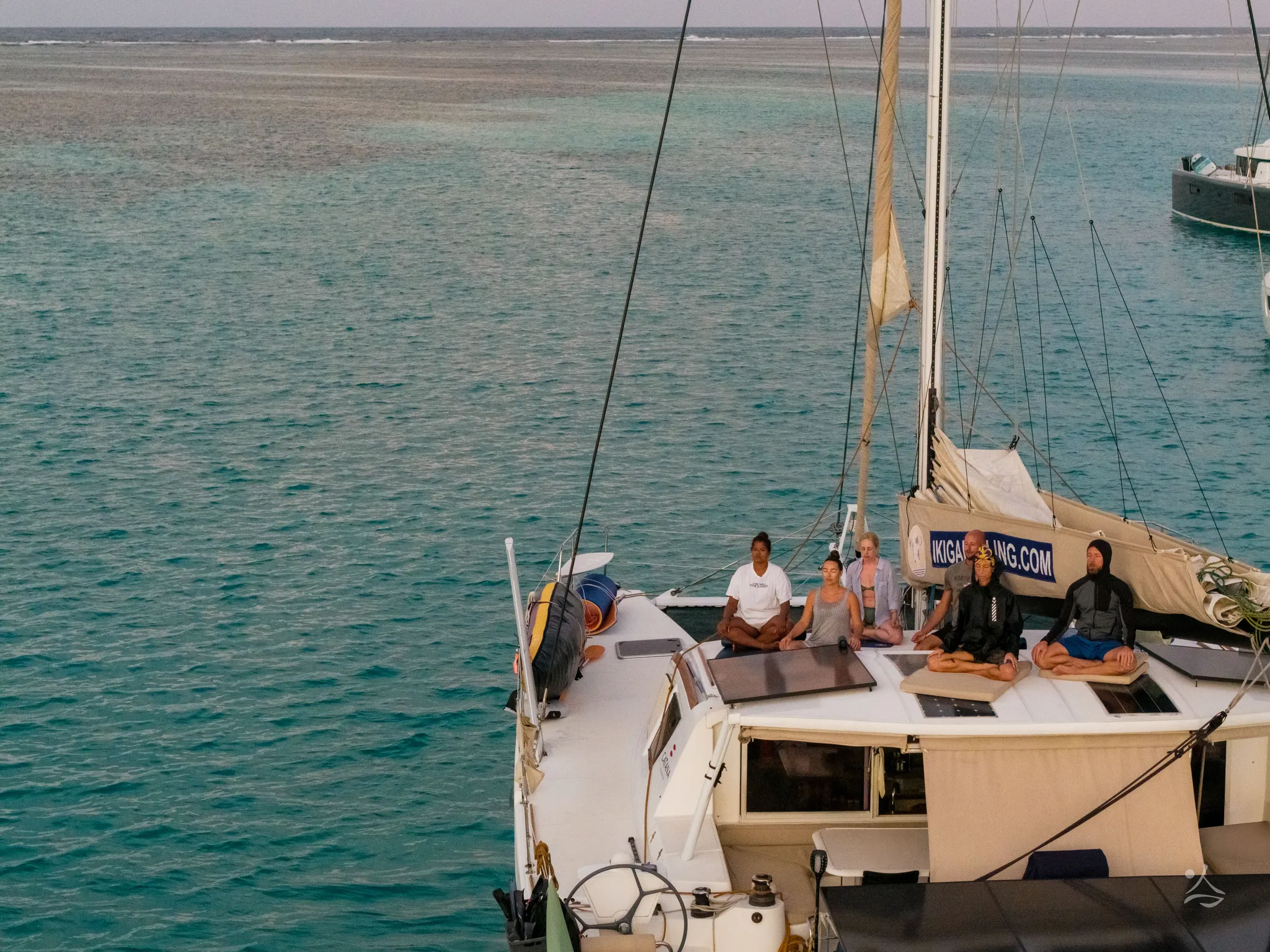 Meditazione di gruppo in coperta, il catamarano all’ancora visto dall’alto
